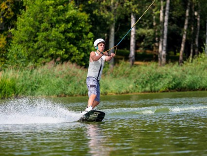 Young man with wakeboard in lake, water sports, water skiing in wakepark