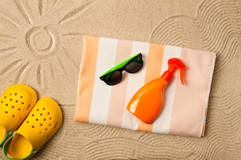 Drawing on the sand, sun and waves, sunglasses, with an orange bottle, yellow rubber slippers,