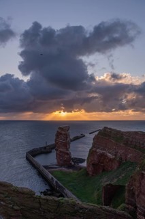 Red sandstone cliff with Lange Anna on the offshore island of Heligoland, mole as protection