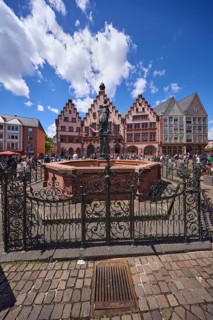 Fountain of Justice and Römer Town Hall on the Römerberg under a blue sky with cumulus clouds in