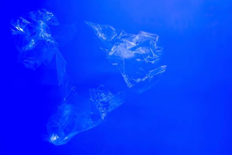 Transparent plastic bags floating underwater in blue ocean sea water, pollution by