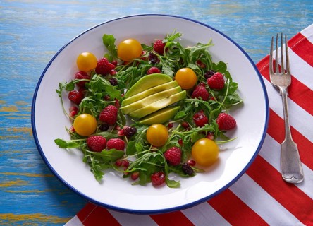 Avocado and berries salad with arugula and yellow cherry tomatoes