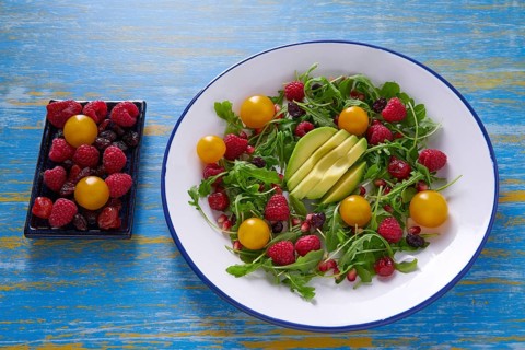 Avocado and berries salad with arugula and yellow cherry tomatoes