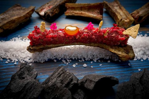 Steak tartar with egg yolk on half bone presentation modern cuisine