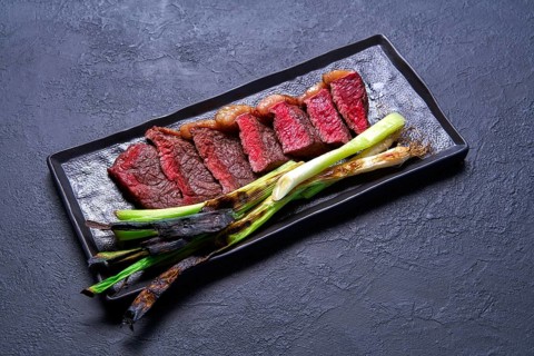 Beef carved meat with grilled fresh garlic on black