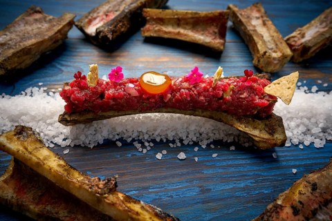 Steak tartar with egg yolk on half bone presentation modern cuisine