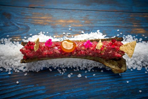 Steak tartar with egg yolk on half bone presentation modern cuisine