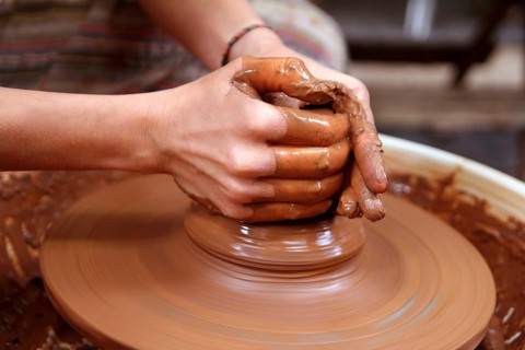 Clay potter hands closeup working on wheel handcrafts pottery work