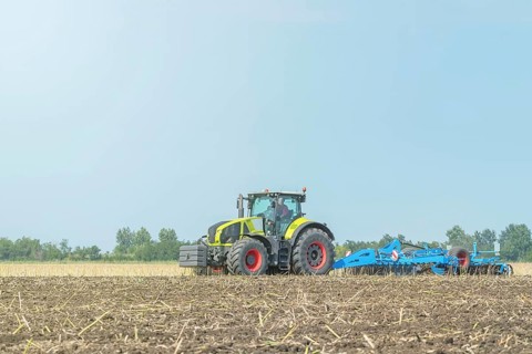 Farmer in tractor preparing land seedbed cultivator. Agriculture tractor landscape