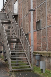 Exterior metal staircase provides access to an industrial building with a brick facade