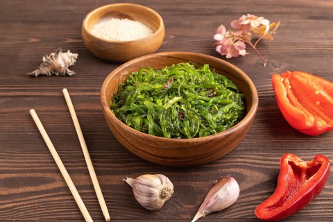 Chuka seaweed salad in wooden bowl on brown wooden background. Side view, close up