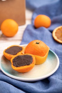 Truffle chocolate tangerine candies on a white wooden background and blue linen textile. Side view,