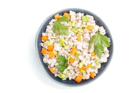 Pearl barley porridge with vegetables in blue ceramic bowl isolated on white background. Top view,