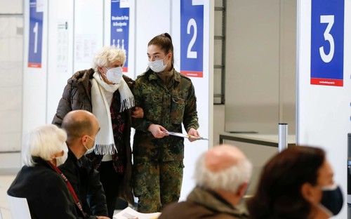 A Bundeswehr soldier brings an elderly woman to the vaccination centre in Terminal 5 of BER