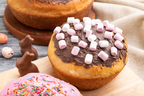 Homemade glazed and decorated easter pies with chocolate eggs and rabbits on a gray wooden