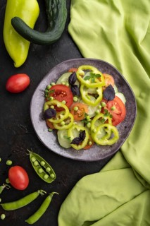 Vegetarian salad from green pea, tomatoes, pepper and basil on a black concrete background and