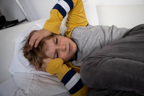 Kind mit Kopfschmerzen, Junge 9 Jahre alt, mit schmerzverzerrtem Gesicht, symbolisches Bild
