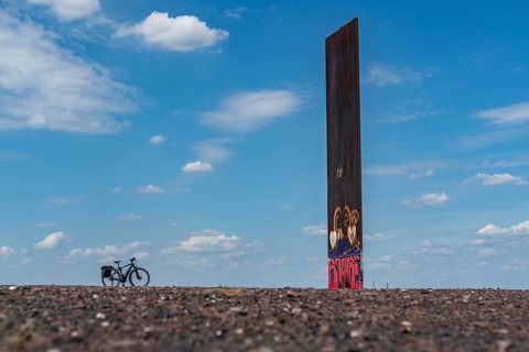 Cycling in the Ruhr area, on the Schurenbach slag heap, Bramme landmark for the Ruhr area by artist