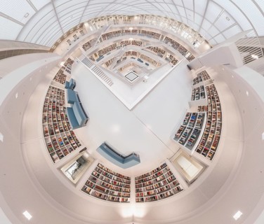 Modern library with symmetrical design and numerous bookshelves in a futuristic white interior,