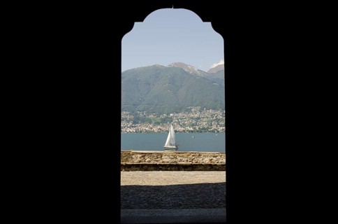 Looking at a Sailing Boat Through an Open Door on Lake Maggiore with Mountain in a Sunny Summer Day
