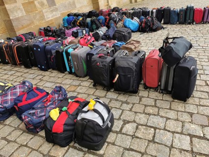 Luggage and rucksacks of different colours and sizes neatly lined up on a paved floor