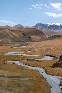 River Kol Suu winds through a mountain valley with hills of yellow grass, Naryn Province,