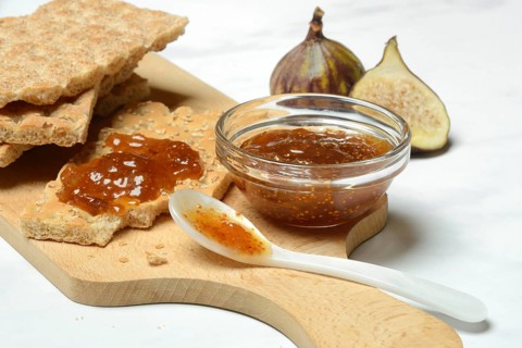 Fig jam in small bowls and on crispbread, Ficus carica