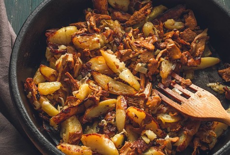 Fried chanterelles with mushrooms, in a clay pan, close-up, top view, selective focus