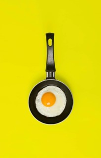 Fried egg, in a small frying pan, on a yellow background, top view