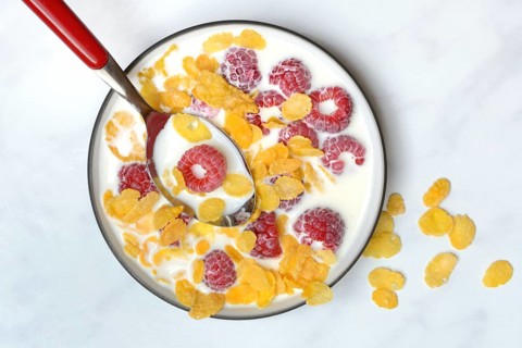 Raspberries and cornflakes with milk in a bowl, Rubus idaeus