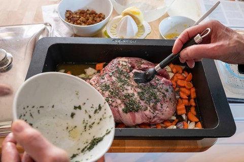 Roast lamb with herbs and vegetables in a casserole in front of roasting, Bavaria, Germany, Europe