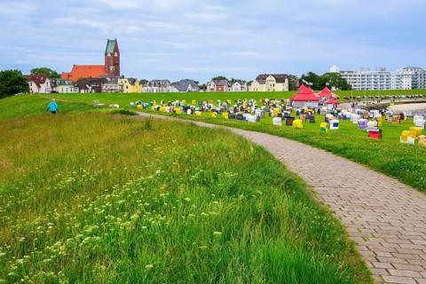 Grassy beach on the dyke with beach chairs and St Peter's Church in the district of Grimmershörn,