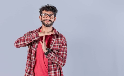 Smiling man gesturing time out isolated. Young Man making time out gesture isolated