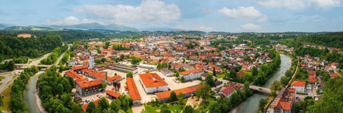 View of a town along a river with red roofs and green surroundings, Traunstein