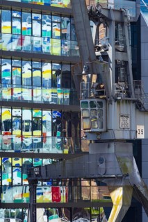 Old crane in front of the glass façade of an office building, reflecting the Colorium high-rise,
