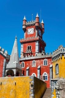Red tower with clock and yellow façade, pointed roof and blue sky, Palácio Nacional da Pena, Pena