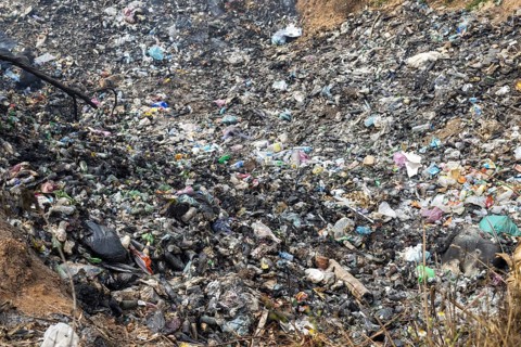 Coking rubbish dump, rubbish pit with waste and plastic rubbish, karst landscape near Vang Vieng,