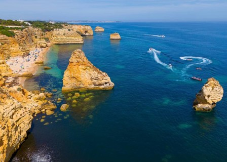 Aerial view of the rocky coast of Algarve, Portugal, with beaches and boats on the blue sea, beach,
