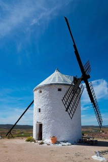 White windmill in a rural landscape under a blue sky on a sunny day with some clouds, Consuegra,