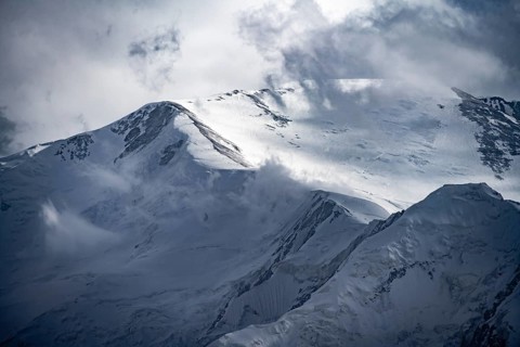 Dramatic mountain landscape, mountain valley, behind glaciated and snow-covered mountain peak Pik