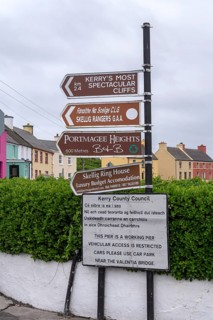 Various signs give directions and clues in a street of colourful houses and grey skies, West Coast,