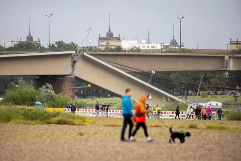 Passers-by look at the partially collapsed Carola Bridge from the Königsufer in Dresden, 11/09/2024