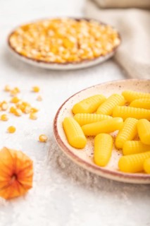 Jelly corn candies on gray concrete background and linen textile. side view, close up, selective