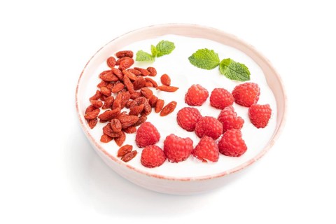Yogurt with raspberry and goji berries in ceramic bowl isolated on white background. Side view,