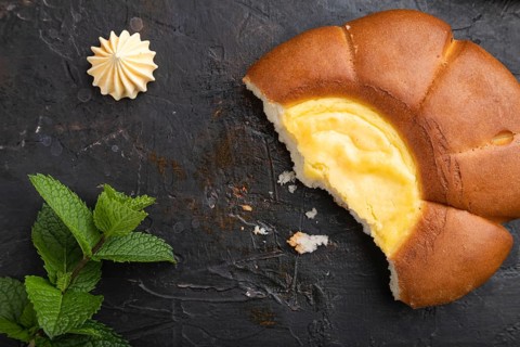 Sour cream bun with cup of coffee on a black concrete background and linen textile. top view, flat