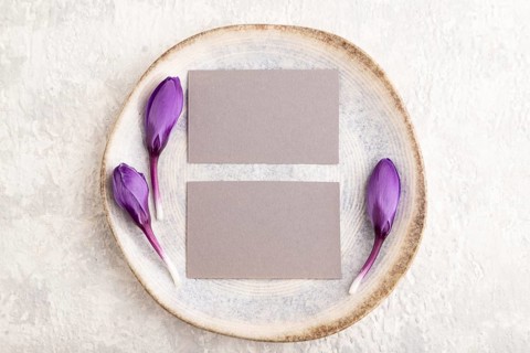 Gray paper invitation card, mockup with crocus flowers on ceramic plate and gray concrete
