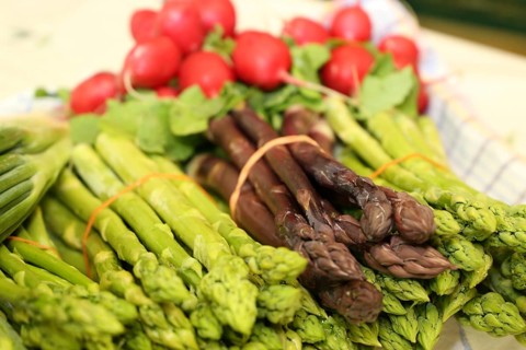 Green and purple asparagus, radishes in the background
