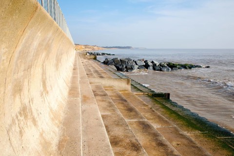 Curved wave return sea wall, steps and rock armour groynes, forming coastal defences at Southwold,