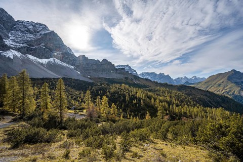 Mountain panorama with steep rocky peaks, yellow-coloured larches in autumn, hike to the summit of