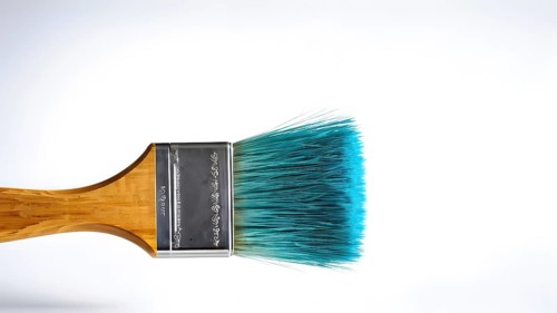 Thick paintbrush dipped in cyan bristles dripping onto a white background, AI generated